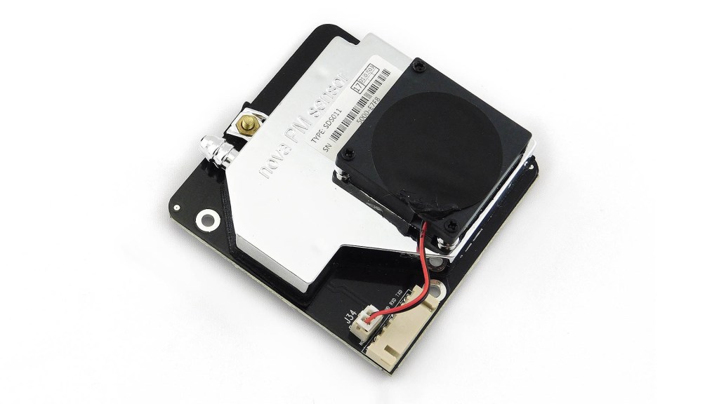 Photo of Nova PM sensor. Square board, ~5cm on each dimesion, with a metal block on top of it, and then a small fan on top of that.